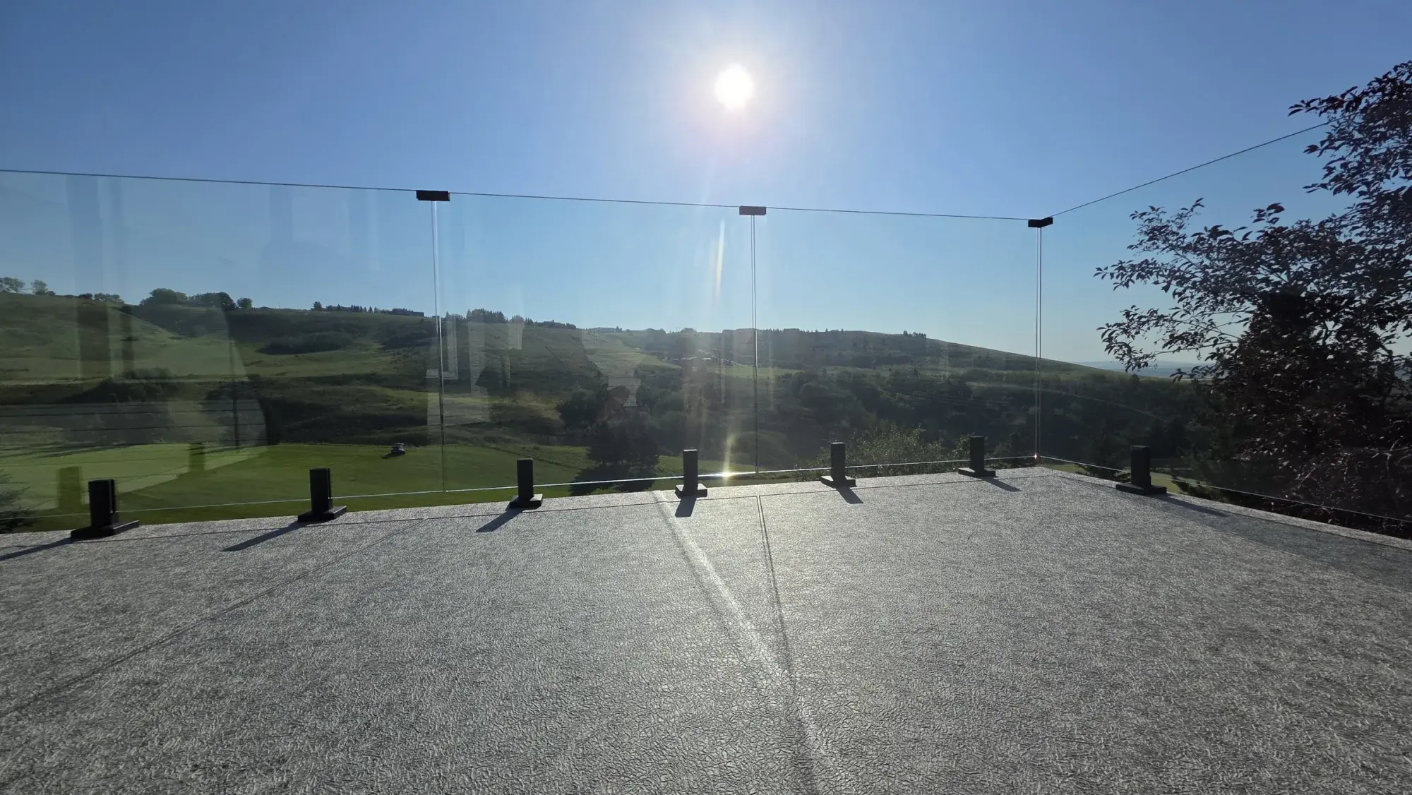 A granite-finish vinyl deck in full sun, looking out over the fairway and hills