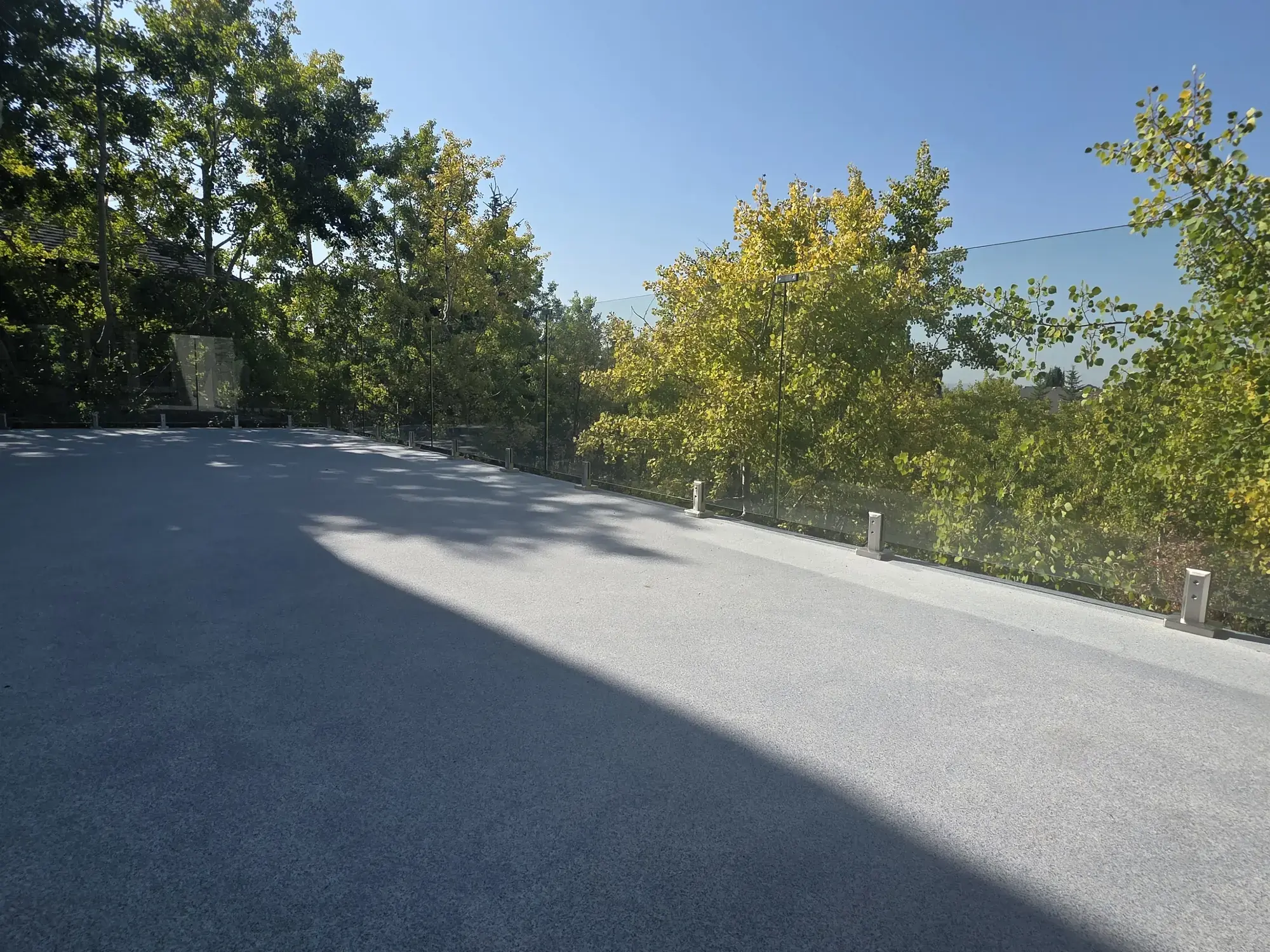 A granite vinyl deck under autumn aspens, glass railing, clear blue sky