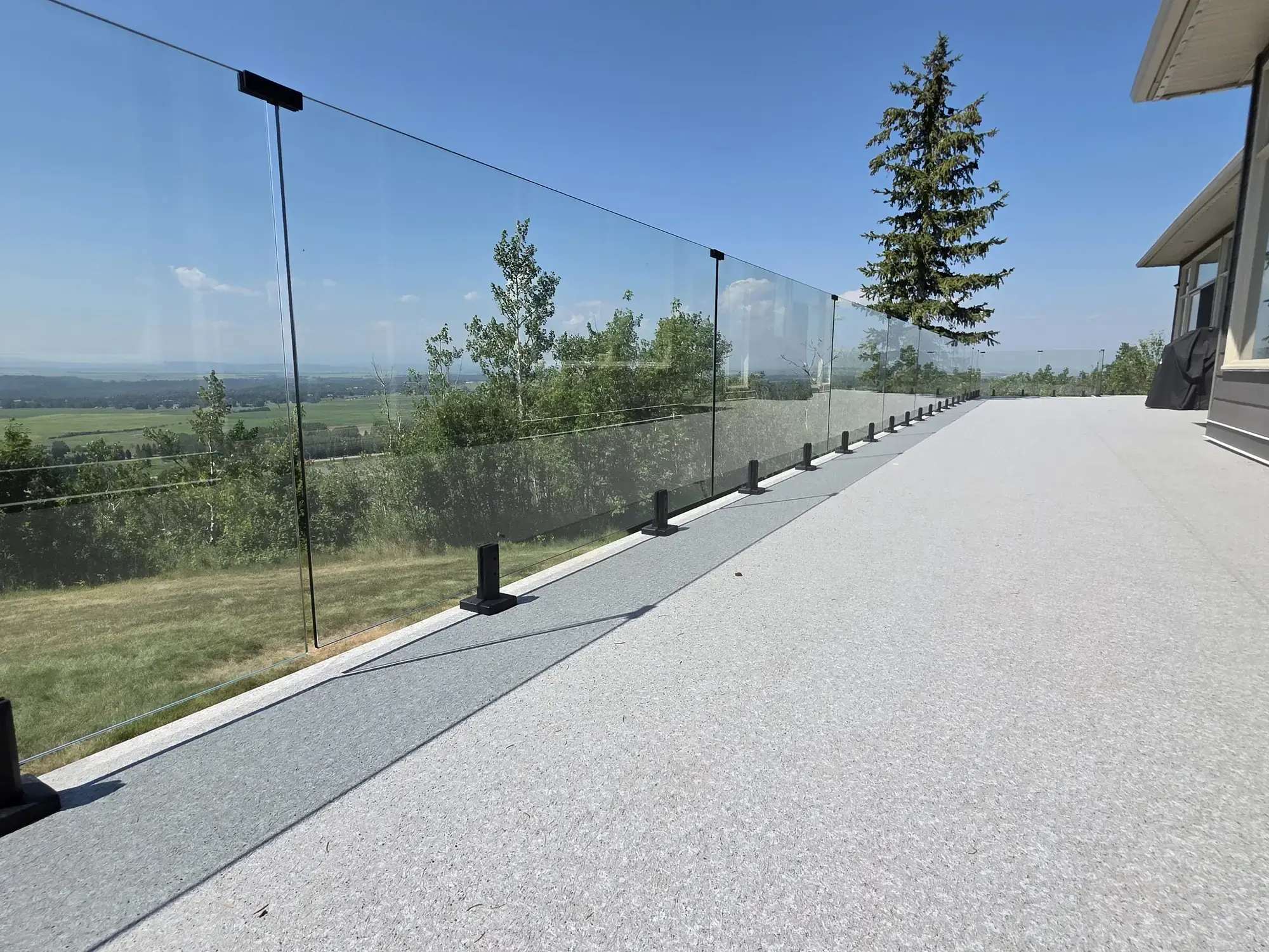 A long granite vinyl deck running to a glass railing, prairie horizon beyond
