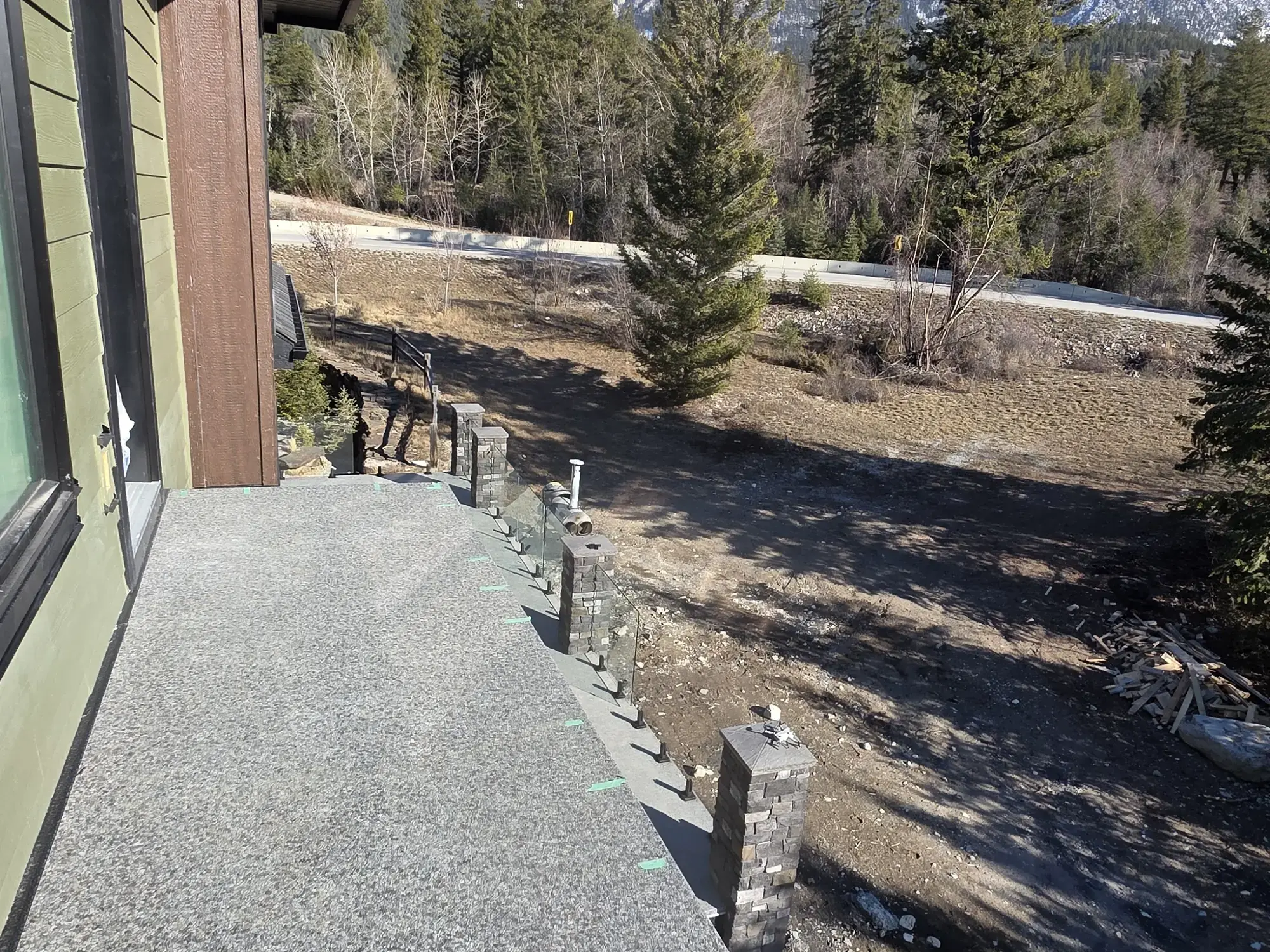 An elevated vinyl deck with glass railing, looking out over a hillside